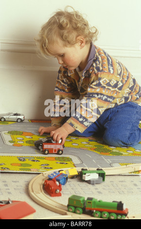 Ragazzo giocando con le automobili e treni di legno via Foto Stock