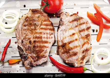 Braciole di maiale alla griglia sulla griglia in alluminio pan Foto Stock