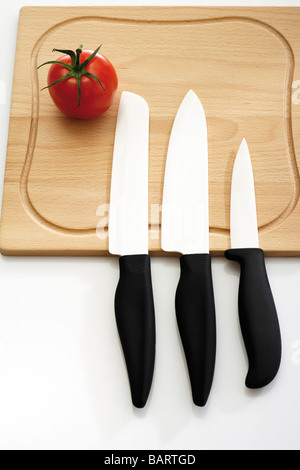 Pomodoro e coltelli sul tagliere, vista in elevazione Foto Stock