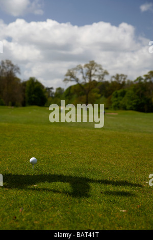 Utilizzate la pallina da golf seduti sul tee con ombra di un golfista circa per colpire la palla all'inizio di un campo da golf Foto Stock