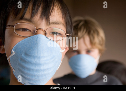 Primo piano dei due figli di età 12 e 10 di indossare le maschere Foto Stock