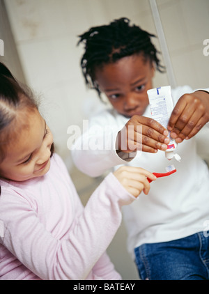 Spazzolare i denti. Bambina di cinque anni e ragazzo mettere il dentifricio sullo spazzolino Foto Stock