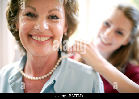 Madre e figlia. Figlia il fissaggio di una collana di perle attorno a lei la madre il collo. Foto Stock