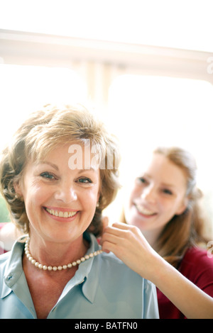 Madre e figlia. Figlia il fissaggio di una collana di perle attorno a lei la madre il collo. Foto Stock