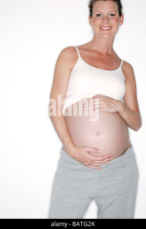 Donna incinta mentre tiene il suo ventre gonfio. Lei è nel suo terzo trimestre. Foto Stock