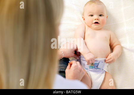 Pannolino cambiando. La madre modifica il suo nove mesi ragazzo del pannolino. Foto Stock