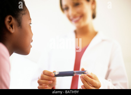 Siringa da insulina. Pazienti diabetici 9 anno vecchia ragazza ascoltando il suo medico spiegare come utilizzare un novopen. Foto Stock