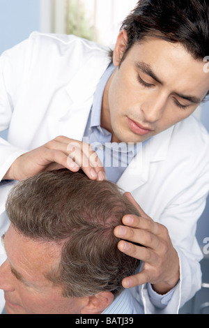 Trapianto di capelli di consultazione. Tricologo esaminando il cuoio capelluto di un uomo che sta contemplando i capelli chirurgia dei trapianti. Foto Stock