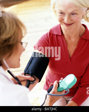 Modello rilasciato sfigmomanometro stetoscopio e essendo usato da un medico per misurare un 63-anno-vecchia donna di pressione del sangue. Foto Stock