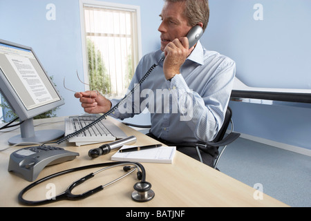 Medico di medicina generale al lavoro nel suo ufficio. Foto Stock