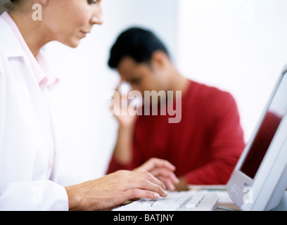 Consultazione medica. Pratica generale medico digitando le note durante la consultazione con il paziente di sesso maschile. Foto Stock