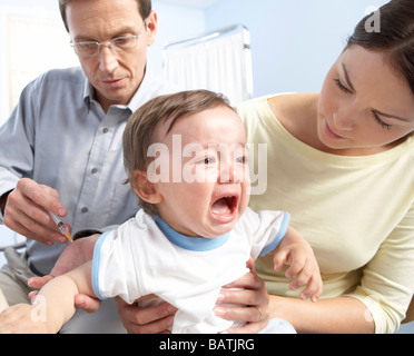 La vaccinazione di infanzia. Un anno vecchio ragazzo ricezione di un'iniezione da un GP. Foto Stock