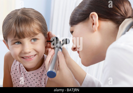 Esame dell'orecchio. Otoscopio essendo utilizzato da una pratica generale medico per esaminare un sei-anno-vecchia ragazza l orecchio. Foto Stock