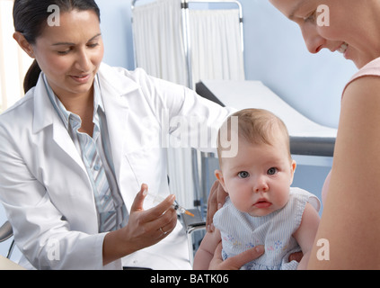 La vaccinazione. 5-mese-vecchio bambina avente un vaccino iniettato nel suo braccio da una siringa. Foto Stock