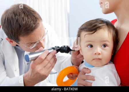 Esame dell'orecchio. Otoscopio essendo utilizzato da una pratica generale medico per esaminare un uno-anno-vecchio ragazzo l orecchio. Foto Stock