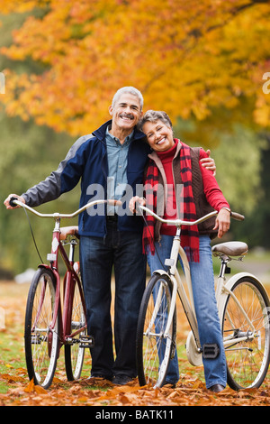 African matura in piedi con le biciclette nel parco in autunno Foto Stock