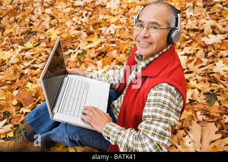 Uomo ispanico che indossano le cuffie utilizzando laptop Foto Stock