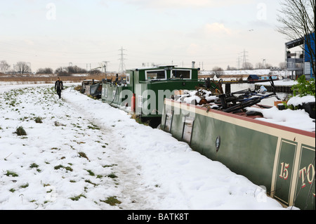 Donna che cammina lungo la strada alzaia attraverso la neve accanto alla Lea valle canal,con case galleggianti ormeggiate,Walthamstow paludi Foto Stock