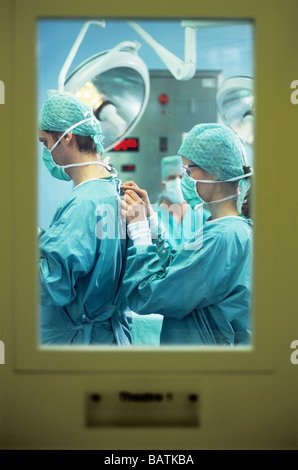 La preparazione per la chirurgia.Theatre nurse assistere ad un chirurgo di abito. Questa tecnica impedisce la contaminazione del chirurgo nelle sue mani. Foto Stock