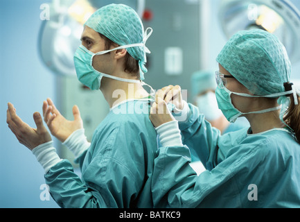 La preparazione per la chirurgia.Theatre nurse assistere ad un chirurgo di abito. Questa tecnica impedisce la contaminazione del chirurgo nelle sue mani. Foto Stock