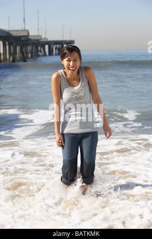 Donna asiatica wading molo vicino alla spiaggia Foto Stock