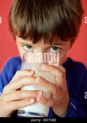 Il latte destinato al consumo umano. 7-year-old boyholding un bicchiere di latte. Il latte è una buona fonte ofcalcium,che è necessaria per ossa forti andteeth. Foto Stock