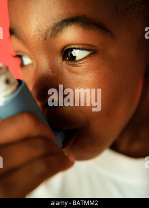 Ragazzo asmatici usando il suo inalatore. L'asma è una condizione in cui le piccole vie aeree (bronchioli) nei polmoni restringersi. Foto Stock