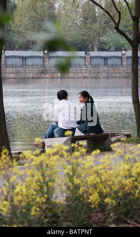 Coppia seduta dal lago in East Garden, Suzhou, Cina Foto Stock