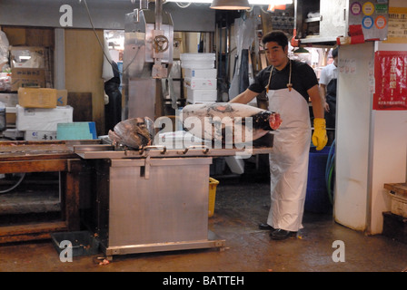 Lavoratore nel mercato del pesce Tsukiji Tokyo Giappone tagli del tonno congelato testa di pesce off Foto Stock