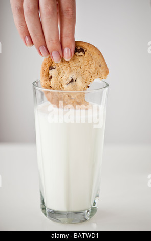 Donna di mano cookie di immersione nel bicchiere di latte Foto Stock