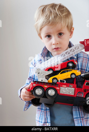 Ritratto di ragazzo (4-5) azienda toy motore fire e automobili Foto Stock