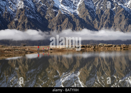 Il Remarkables e famiglia riflessa a piedi in cima Tarn Deer Park Heights vicino a Queenstown Isola del Sud della Nuova Zelanda Foto Stock
