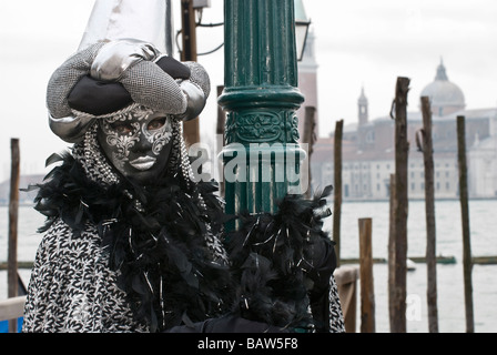 Carnevale veneziano camuffare con un nero e Silver mask pennacchi di nero e guanti in prossimità di un lampione in San Marco Foto Stock