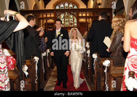 Giovane coppia di sposi novelli a piedi giù per la navata della chiesa North Yorkshire. Modello Regno Unito rilasciato Foto Stock