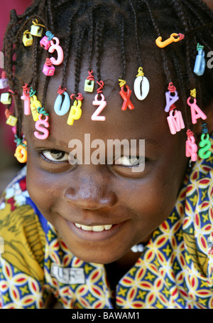 Ragazza sorridente con lettere nel suo dreadlocks, Guinea, Africa occidentale Foto Stock