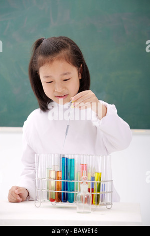 Ragazza con tubo di prova nella parte anteriore di blackboard guardando verso il basso Foto Stock