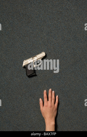 La mano di una donna morta e una pistola in una scena del crimine Foto Stock