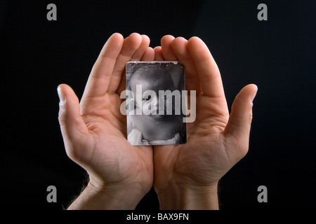 ATwo mani hanno una piccola in bianco e nero alterò la foto di un po' di baby boy Foto Stock