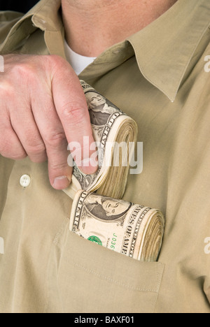 Un uomo luoghi mazzette di denaro contante nella sua tasca della camicia Foto Stock