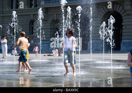 Bambini che giocano nella trick fontane e giardini d'acqua davanti alla Casa del Parlamento sulla piazza del Parlamento, Bundeshaus (Parlamento), Foto Stock