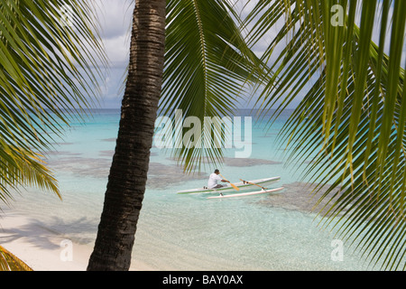 Uomo su una canoa outrigger paddling in Fakarava Laguna, Fakarava, Tuamotus, Polinesia Francese Foto Stock