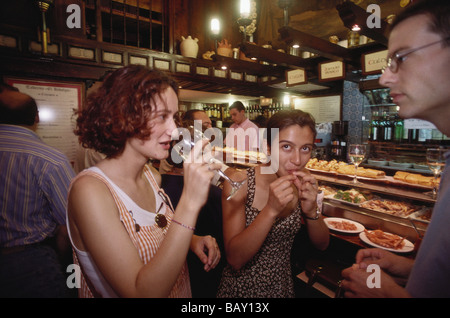 Due giovani donne e un giovane uomo beve vino e degustazione delle tapas dal contatore in un bar a Valladolid, Castiglia-Leon, né Foto Stock