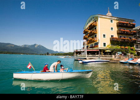 La famiglia in una barca elettrica che arriva san Wolfgang, Hotel Im Weissen Roessel am Wolfgangsee in background, St. Wolfgang, Superiore Aus Foto Stock