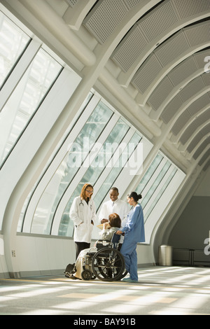 Multi-etnico medici e infermieri con paziente in sedia a rotelle Foto Stock