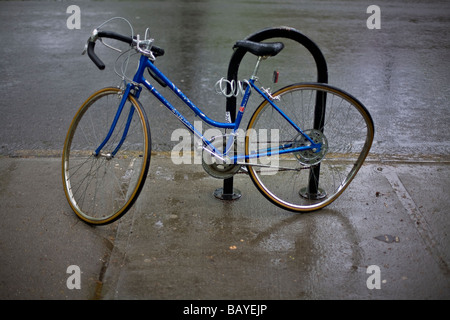 Bicicletta con ruota inclinata concatenati a un sondaggio Foto Stock