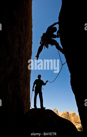 Un team di arrampicatori si stagliano in quanto lavorano a loro modo su un camino Foto Stock