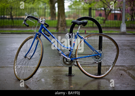 Bicicletta con ruota inclinata concatenati a un sondaggio Foto Stock