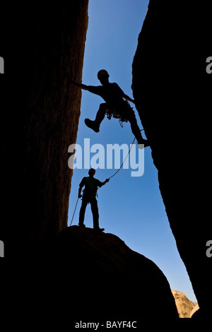 Un team di arrampicatori si stagliano in quanto lavorano a loro modo su un camino Foto Stock