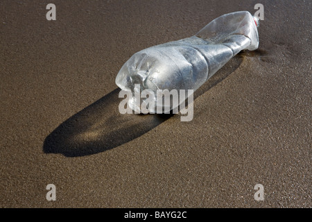 La bottiglia di plastica lavati fino sulla spiaggia sabbiosa Foto Stock