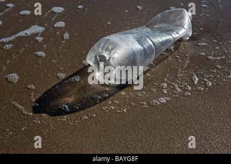 La bottiglia di plastica lavati fino sulla spiaggia sabbiosa Foto Stock